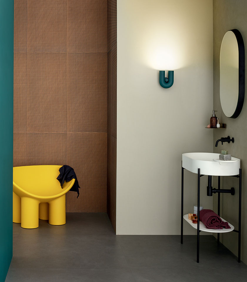 Bagno moderno con superfici materiche, tonalità neutre e accenti di colore vivaci.