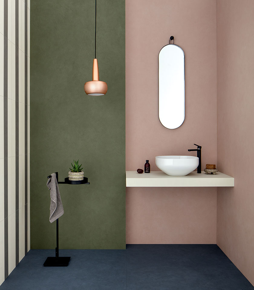 Bagno moderno con pareti colorate in verde e rosa, superfici essenziali e dettagli dal design minimale.