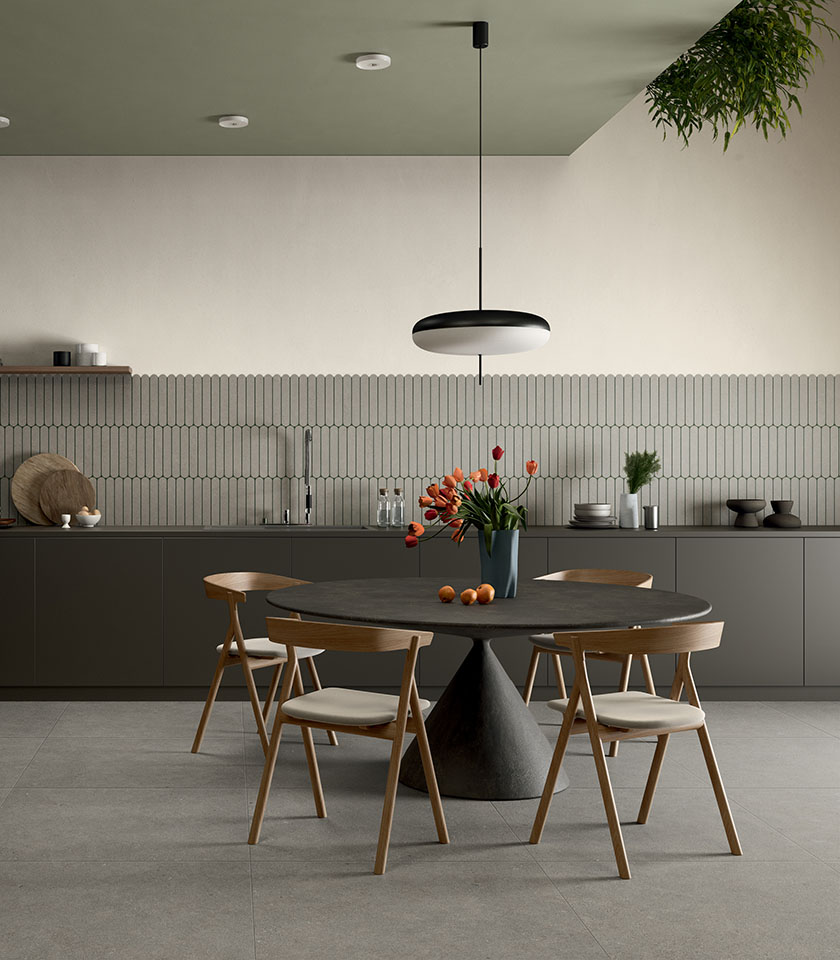 Zona pranzo contemporanea con tavolo scuro e sedie in legno, pavimento della collezione Intense effetto pietra Crete Clair e rivestimento decorativo Pills Crete.