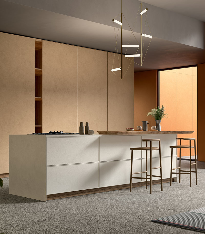 Cucina contemporanea con isola centrale e sgabelli, rivestimenti della collezione Pigmenti nelle tonalità Harvest, Mist e Sunset, abbinati a pavimento Piece Dark.