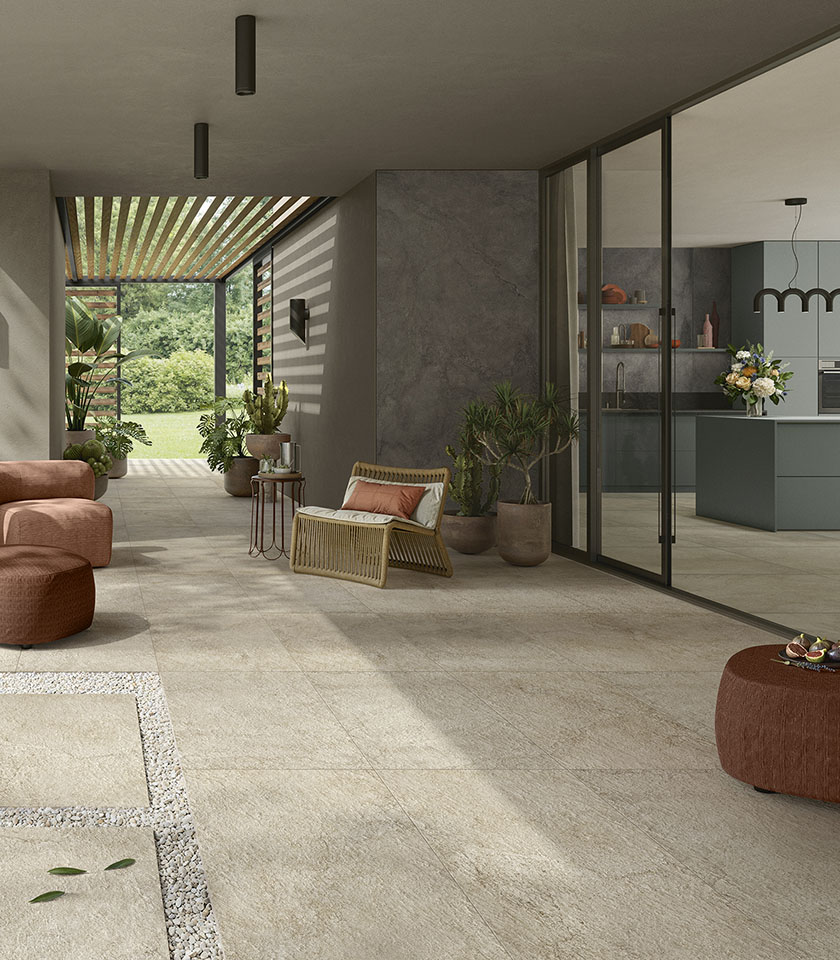 Spazio living contemporaneo indoor-outdoor con pavimento della collezione Pulse effetto pietra nella tonalità Sand Rough e rivestimenti nella tonalità Shadow.