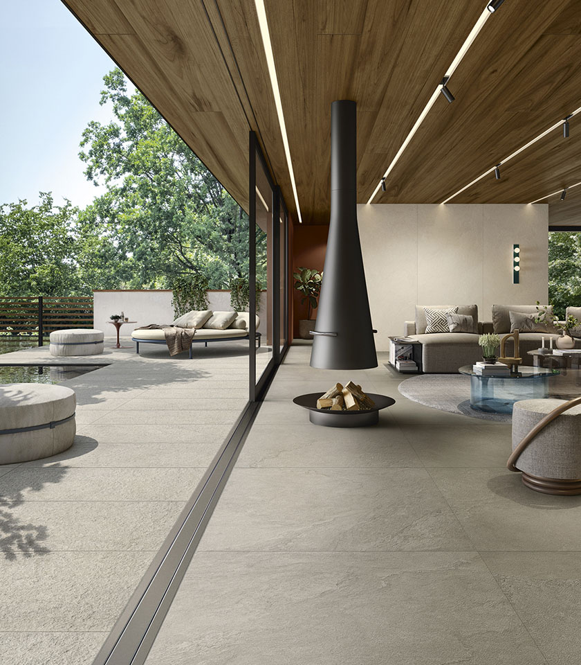 Spazio living contemporaneo indoor-outdoor con pavimento della collezione Pulse effetto pietra nella tonalità Clay, finitura Clay Rough per l’esterno e rivestimenti nella tonalità Shell.