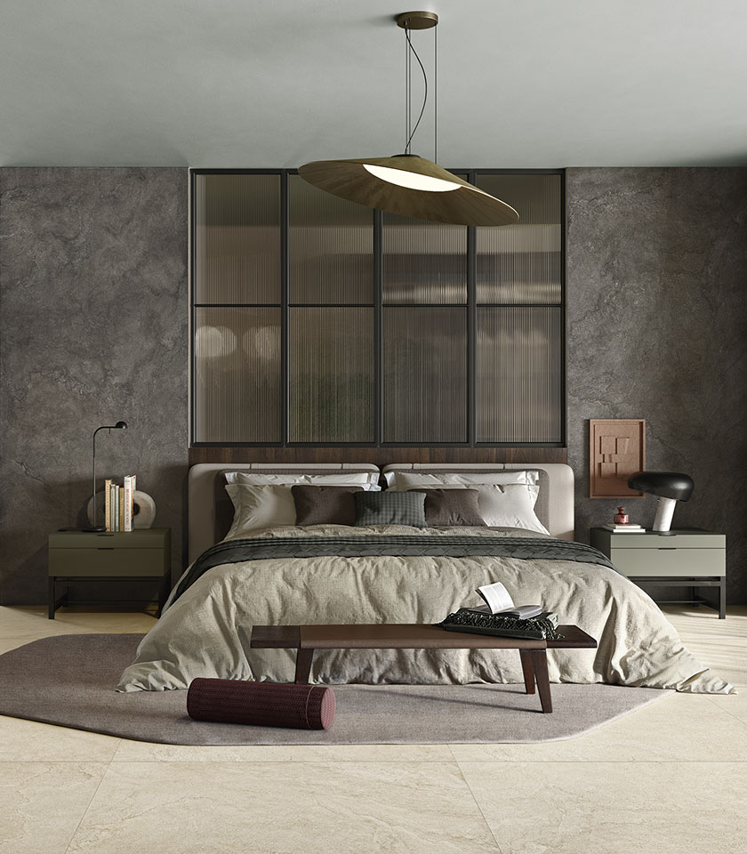 Camera da letto contemporanea con pavimento beige effetto pietra, pareti scure materiche e arredi dalle tonalità neutre.