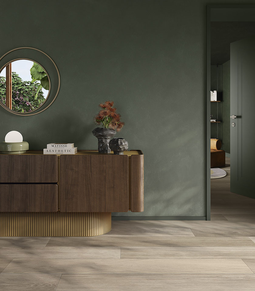Interno contemporaneo con pavimento effetto legno Biocharme Havana, pareti verde salvia e arredi in legno dalle linee eleganti.