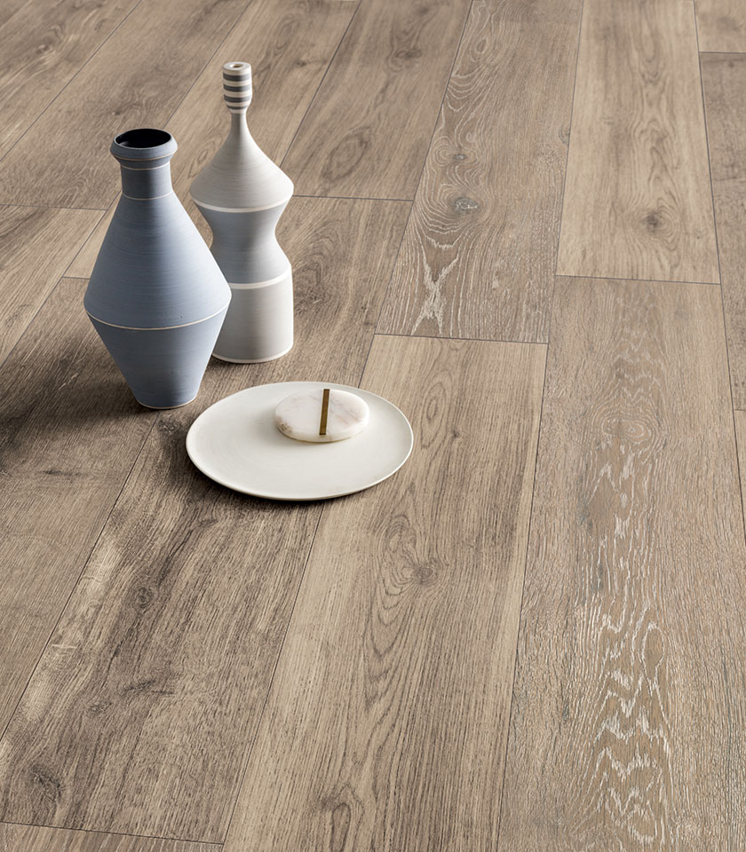 Pavimento in gres porcellanato effetto legno in tonalità naturale, con venature realistiche e oggetti decorativi in ceramica.