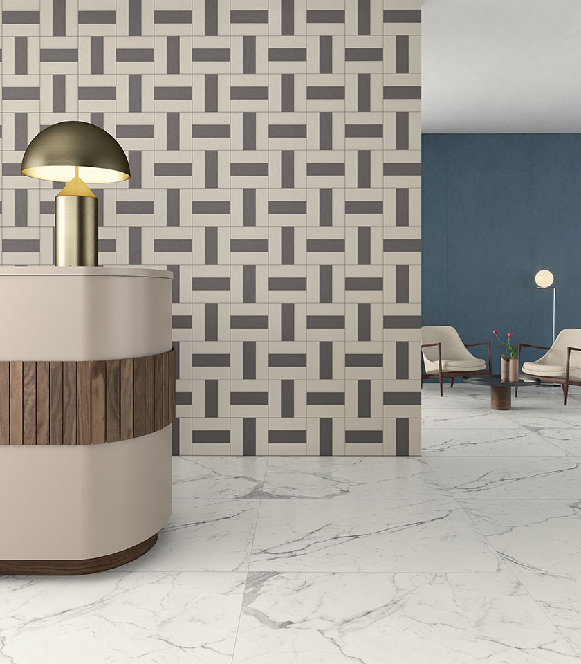 Spazio reception contemporaneo con pavimento in gres porcellanato effetto marmo, parete decorativa geometrica e rivestimento blu.
