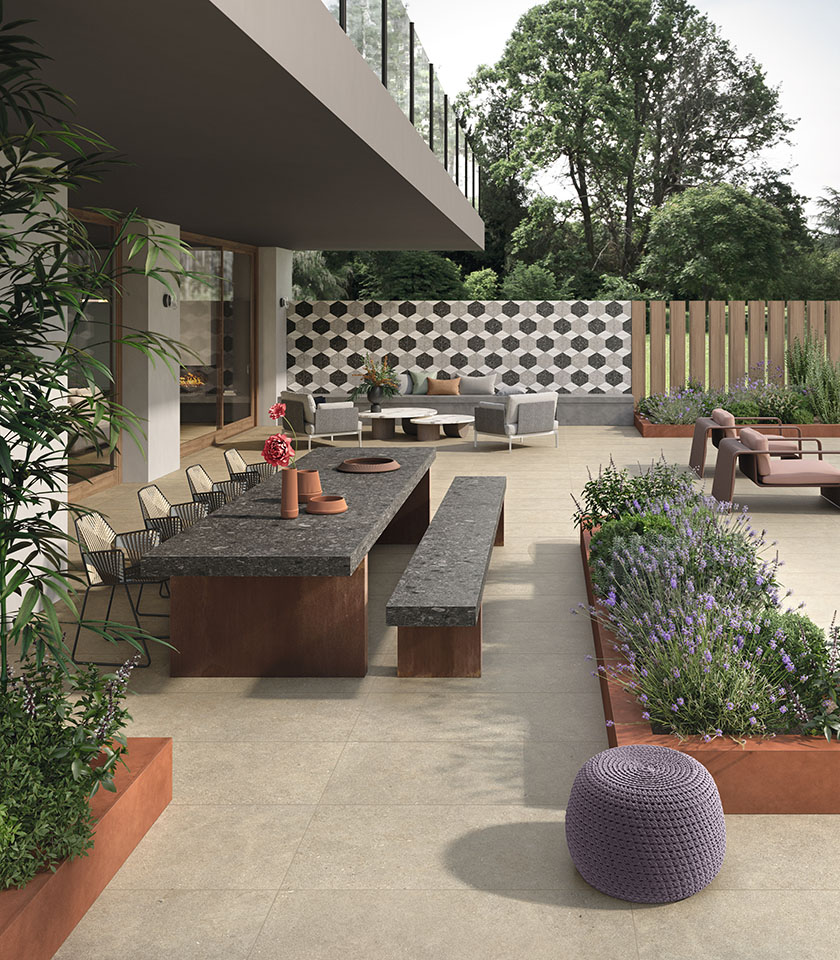Spazio outdoor contemporaneo con pavimento della collezione Intense effetto pietra nella tonalità Toffee, superfici Sidestone Cluster Dark, parete decorativa con mosaico Sidestone Omega ed elementi Pigmenti Canyon.