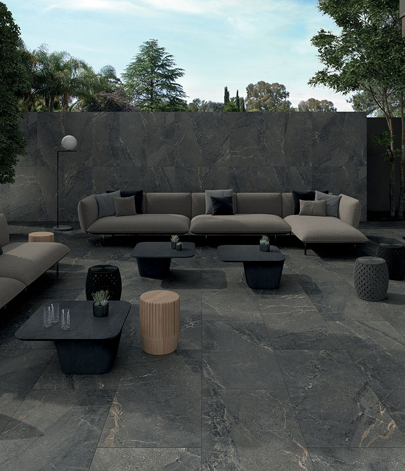 Anthology Dark Rough veste gli spazi outdoor con eleganza materica: superfici ceramiche scure, effetto pietra e grande continuità tra pavimento e rivestimento.