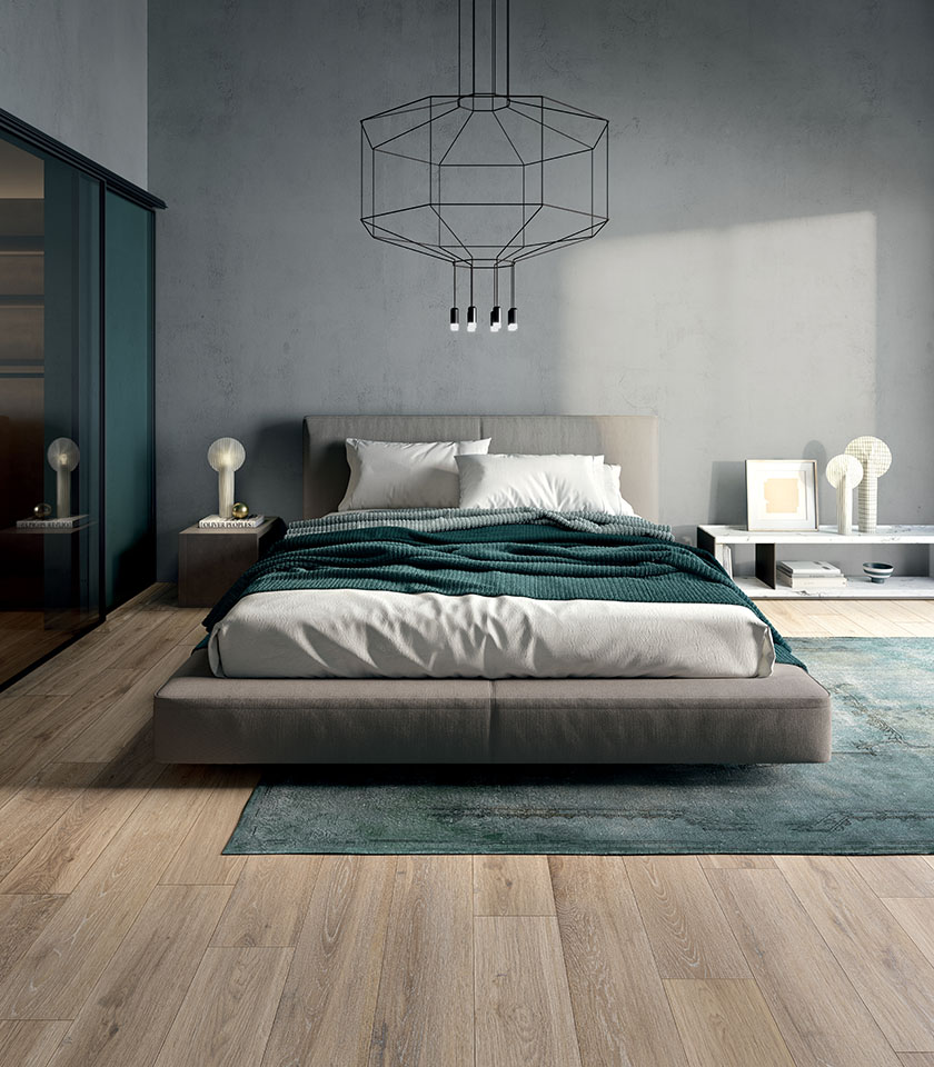 Camera da letto in stile Japandi con pavimento in gres porcellanato effetto legno, letto basso, arredi minimalisti e tonalità neutre.