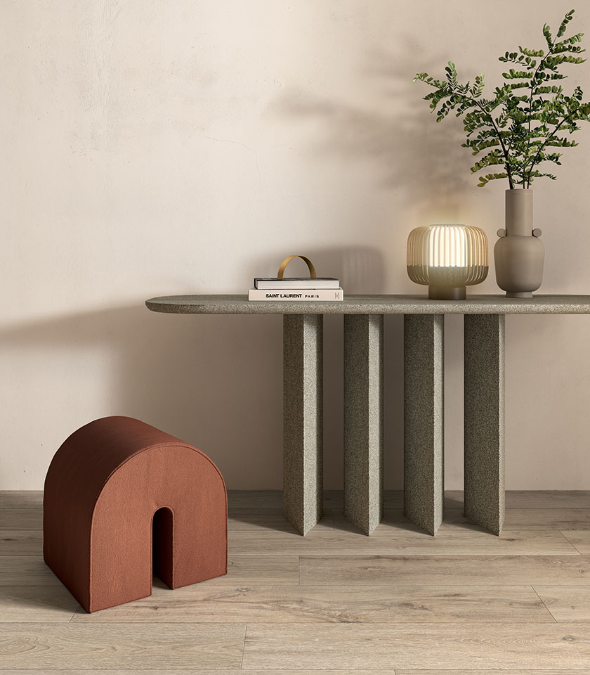 Interno in stile Japandi con pavimento in gres porcellanato effetto legno, consolle scultorea, seduta bassa e decorazioni naturali.