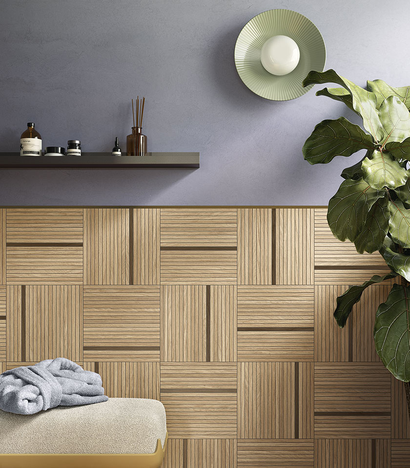 Bagno contemporaneo con rivestimento decorativo effetto legno a moduli geometrici, parete grigia e grande pianta verde.