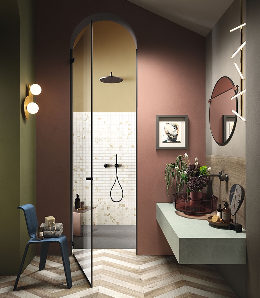 Bagno dal carattere sofisticato con pavimento effetto legno a spina di pesce, mosaico effetto marmo e tonalità avvolgenti per un ambiente originale e contemporaneo.