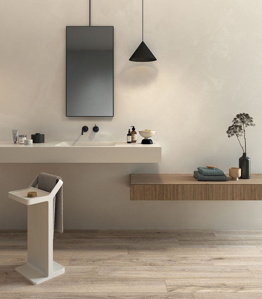 Bagno minimalista con pavimento effetto legno chiaro, arredi sospesi e tonalità neutre per un ambiente essenziale, luminoso e rilassante.